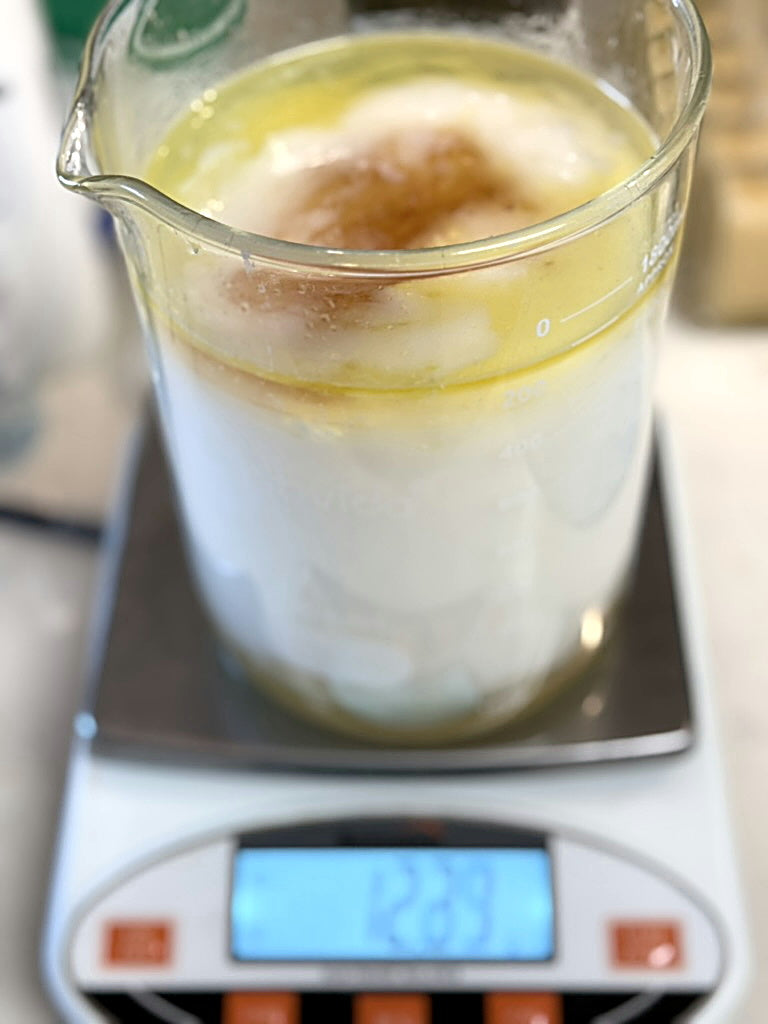 A glass beaker of formula on a scale at the formulation bench