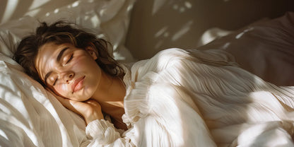 A woman resting on white bedding in soft morning light