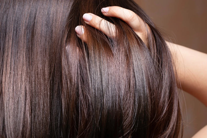 Hand gliding through sleek, glossy brown hair after using Murumuru Rich Reconstruction Hair Mask